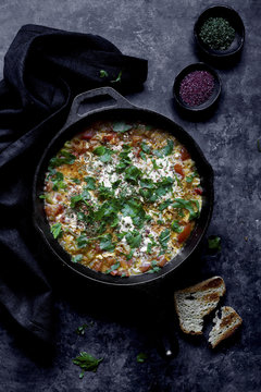 Shakshuka a dish of eggs poached in a sauce of tomatoes, chili peppers, and onions, spiced with cumin.