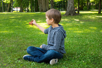 Child sitting on the grass and playing with spinner