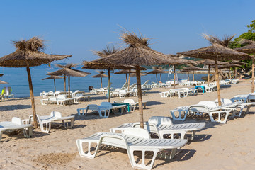 Black sea, sand beach with straw umbrellas and white sun chairs, Balchik, Bulgaria