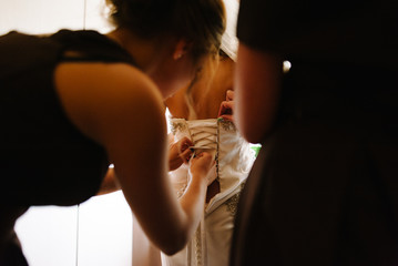 Mother hand lace up corset on bride's delicate waist