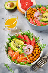 Healthy salad bowl with salmon, grapefruit, spicy chickpeas, avocado, red onion and arugula