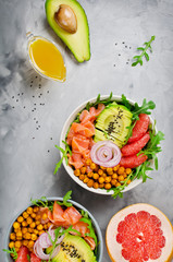 Healthy salad bowl with salmon, grapefruit, spicy chickpeas, avocado, red onion and arugula