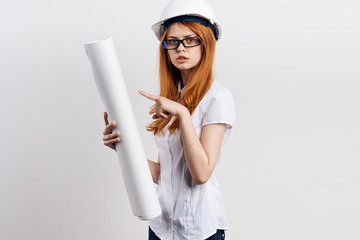Young beautiful female engineer holding blueprints on white isolated background