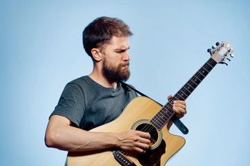 Obraz premium Young guy with a beard on a blue background playing the guitar