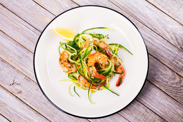 Shrimp with zucchini noodles. Prawns with vegetables and lemon. View from above, top studio shot