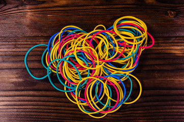 Multicolored rubber bands on wooden table. Top view