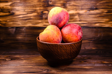 Peaches in a bowl on wooden table