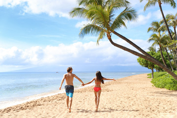 Hawaii beach couple happy having fun running with arms up. Happy freedom people on Kaaanapali beach, Maui, USA.