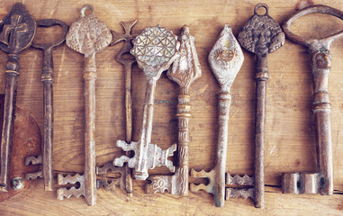Set of rusty keys on wooden background. Vintage collection of old door keys in retro style for your concept of treasure or medieval secret.