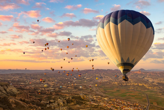 Cappadocia landscape at sunrise - hot air balloons flying over mountain valley in Goreme, wide panorama.