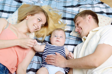 Obraz premium Young happy family with their infant boy on the floor