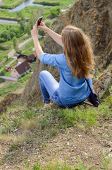 Young girl in blue clothes, wearing sunglasses doing selfie in summer outdoors