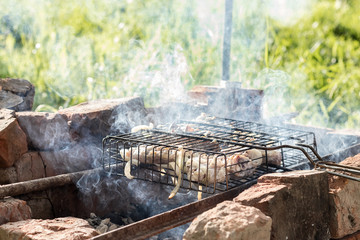 Preparing meat on a steel grate for grill. Smoke from the hot coals. Outdoor cooking