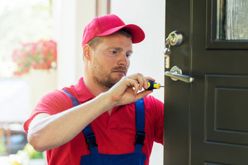 locksmith in red uniform installing new house door lock - obrazy, fototapety, plakaty