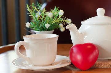 White tea pot and cup with Tea strainer on wooden table, relaxing with hot tea during tea break.