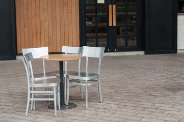 Wooden table and silver chairs set in front of coffee cafe.
