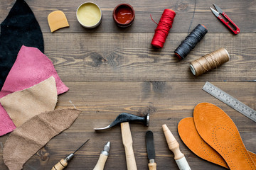 Set of cobbler tools on brown wooden desk background top view copyspace