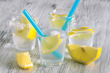 Citrus lemonade with lemon wedges and blue straw.Cold drink with lemon and ice cubes.