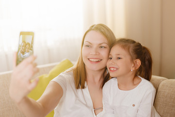 Beautiful mother and young daughter making a selfie.