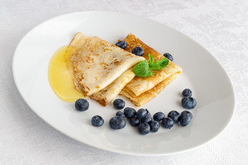 pancakes with honey and blueberries decorated with mint leafs