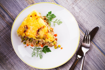 Traditional shepherd pie. Meat, potato, cheese, carrot, onion and green peas casserole. View from above, top studio shot