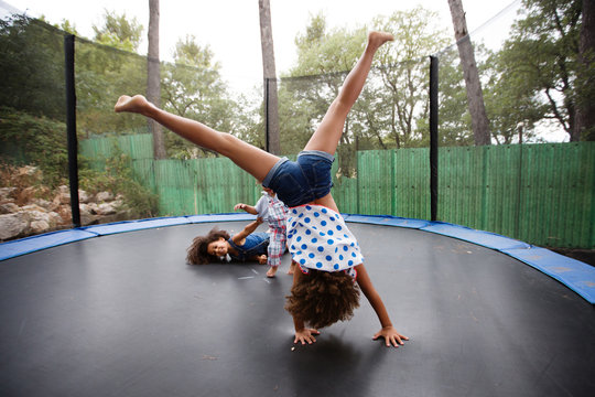 girl doing handstand on trampoline with siblings