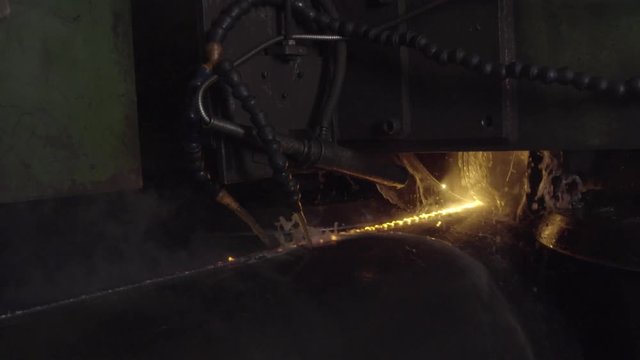 Welder complete with personal protective equipment is perform pipe welding in dark area using Automatic Welding System. Welding sparks spreading everywhere. Automat welding pipe production