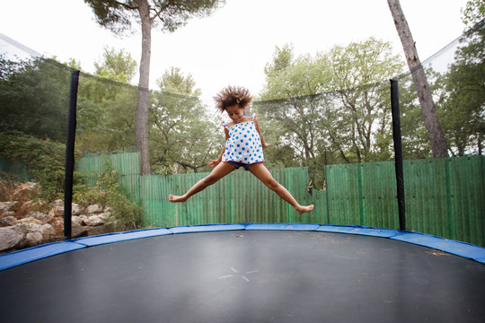 girl with afro hair bouncing on trampoline