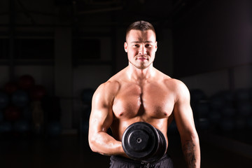 Naklejka na ściany i meble Muscular bodybuilder guy doing exercises with dumbbells.