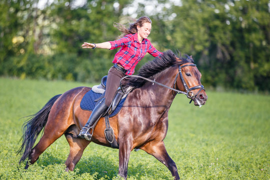 Happy young woman riding galloping horse at sunny summer day. Freedom equestrian concept image