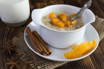 Healthy breakfast: oatmeal with apricot and milk in the glass on the brown wooden background