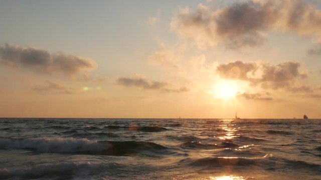 Dramatic sunset with clouds over mediterranean sea, yacht and ship on horizon, Ashdod, Israel.