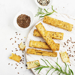 Bread sticks from puff pastry with flax and sesame seeds on a light background with rosemary. Top View.