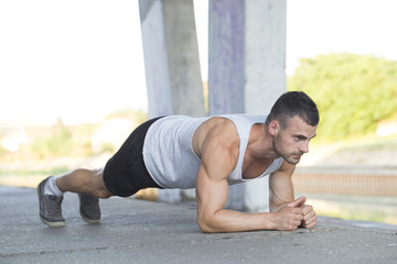 Young muscular young man  doing push ups outdoors