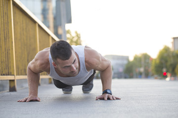 Fototapeta premium Young sportsman doing push ups on the bridge