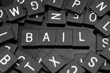 Black letter tiles spelling the word "bail" on a reflective background