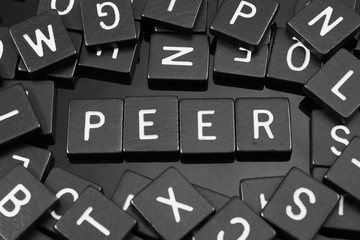 Black letter tiles spelling the word "peer" on a reflective background