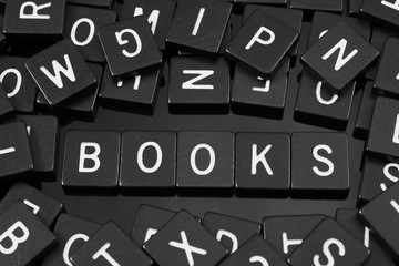 Black letter tiles spelling the word "books" on a reflective background