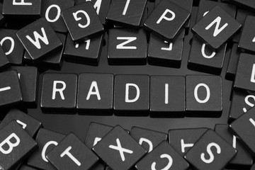 Black letter tiles spelling the word "radio" on a reflective background