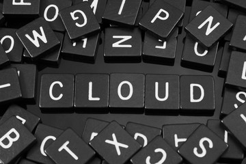 Black letter tiles spelling the word "cloud" on a reflective background