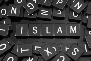 Black letter tiles spelling the word "islam" on a reflective background