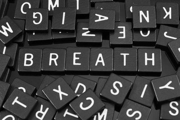 Black letter tiles spelling the word "breath" on a reflective background