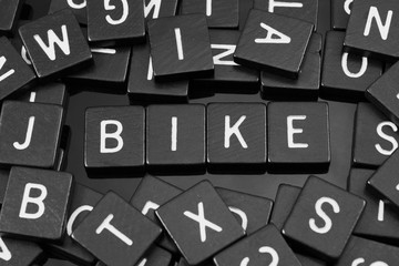 Black letter tiles spelling the word "bike" on a reflective background