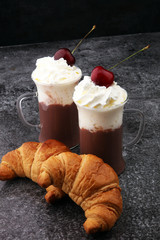 Iced coffee with whipped cream in tall glass and fresh croissant