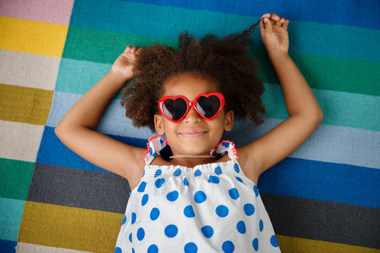 smiling girl with afro hair and heart-shaped sunglasses