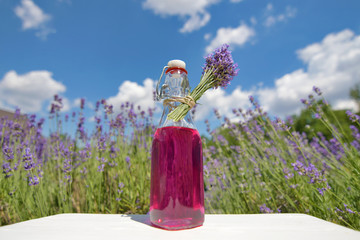 Homemade lavender syrup in a glass bottle in front of lavender