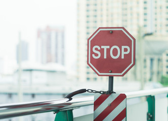 Octagon stop sign at train station with blurred skyscrapers as background, soft and creamy effect