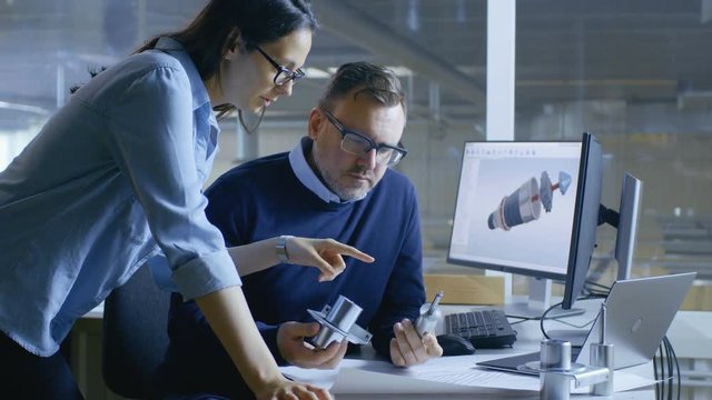 Female Industrial Technician and Male Chief Engineer Designing 3D Turbine/ Engine Model with Help of Cad Software. They Work on a Computer with Two Displays. 4K UHD.