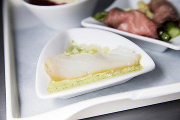 A piece of fish in a sauce like a snack on the plane