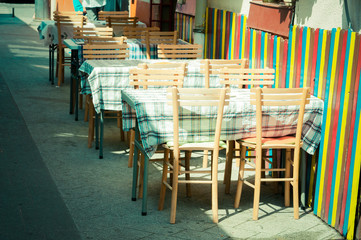 Empty wooden tables and chairs of coffee shop on the street. Selective focus.